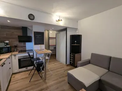 a living room with a couch and a table and a kitchen at Nice Cosy Garden in Nice