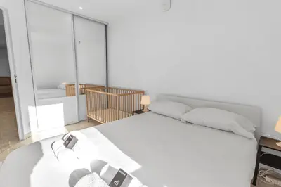 a bedroom with a white bed and a chair at Le Pin - Peaceful - Parking - Comfort - AC in Saint-Laurent-du-Var