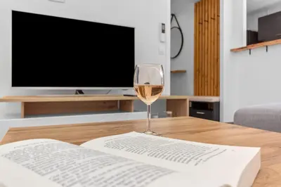 a glass of wine sitting on a table with a book at Le Pin - Peaceful - Parking - Comfort - AC in Saint-Laurent-du-Var