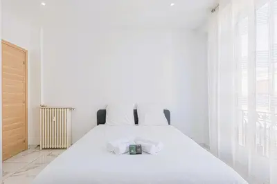a white bedroom with a bed with white sheets at Bail mobilité - Appartement 2 ch - Nice centre in Nice