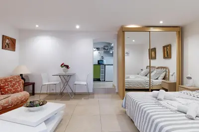 a hotel room with two beds and a living room at Studio indépendant en villa Calme, Jardins et Piscine à 5 min de la Mer in Nice