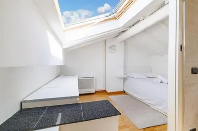 a small attic bedroom with a bed and a window at Duplex à 2 min de la mer à pied in Nice