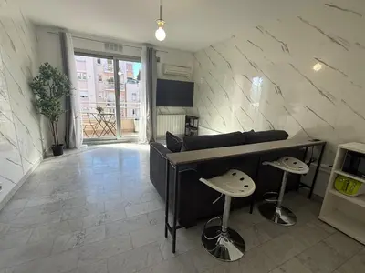 a living room with a couch and a table and stools at La Casa di Gio studio Cosy Tram et mer in Nice