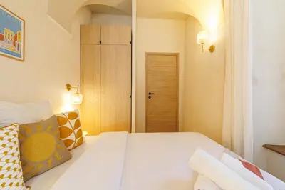 a bedroom with a large white bed with colorful pillows at 62 CARNOT LOT 2 - Un havre de paix climatise avec jardin et jacuzzi in Nice