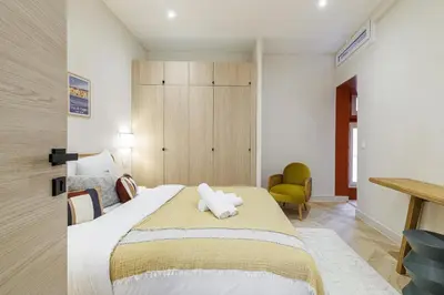 a bedroom with a large bed and a chair at 62 CARNOT LOT 5 - Appartement renove - climatise 2 chambres suites in Nice