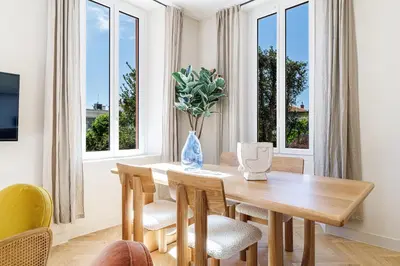 a dining room with a table and chairs and windows at 62 CARNOT LOT 5 - Appartement renove - climatise 2 chambres suites in Nice