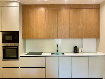 a kitchen with white counters and wooden cabinets at Appartement neuf d architecte Carré d Or in Nice