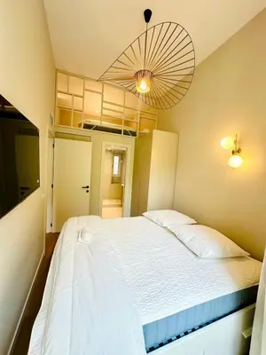 a bedroom with a large white bed and a fan at Appartement neuf d architecte Carré d Or in Nice