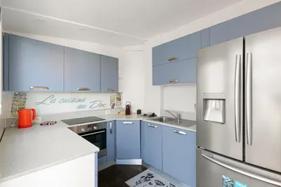 a kitchen with blue cabinets and a stainless steel refrigerator at Suite Lycka FSHH in Nice