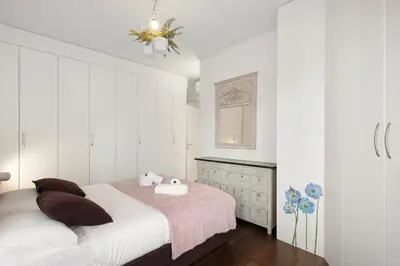 a white bedroom with a bed and a dresser at Suite Lycka FSHH in Nice