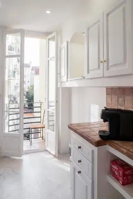 a kitchen with white cabinets and a view of a balcony at Blanche - From Nice with love in Nice