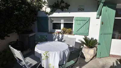 a table with chairs and a window with green shutters at Studio climatisé cosy dans une villa avec parking in Cagnes-sur-Mer