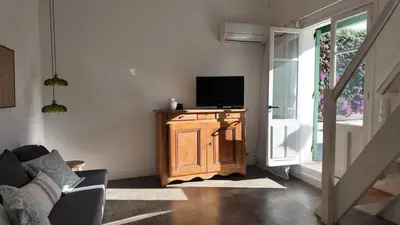 a living room with a television on a wooden stand at Studio climatisé cosy dans une villa avec parking in Cagnes-sur-Mer