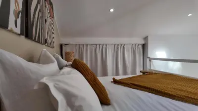 a bedroom with a bed with white sheets and pillows at Studio climatisé cosy dans une villa avec parking in Cagnes-sur-Mer