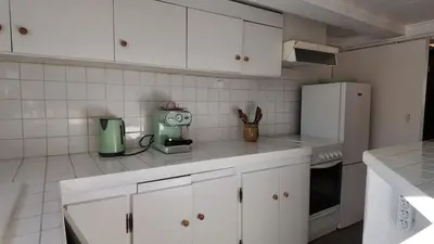 a kitchen with white cabinets and a white refrigerator at Studio climatisé cosy dans une villa avec parking in Cagnes-sur-Mer