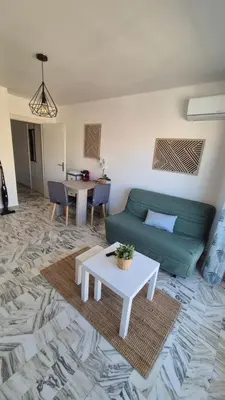 a living room with a green couch and a table at Cosy 1 Bedroom, balcony, Promenade des Anglais in Nice