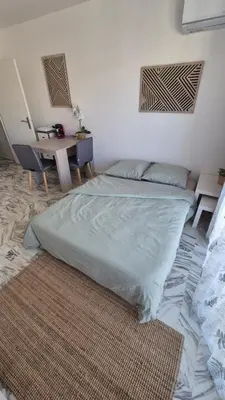 a bedroom with a bed with a table and a rug at Cosy 1 Bedroom, balcony, Promenade des Anglais in Nice