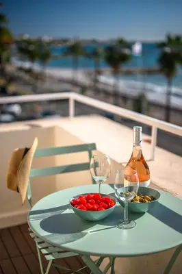 a table with two wine glasses and a bowl of tomatoes at Vue mer panoramique - Cocon cosy et luxe - Clim et Wifi in Cagnes-sur-Mer