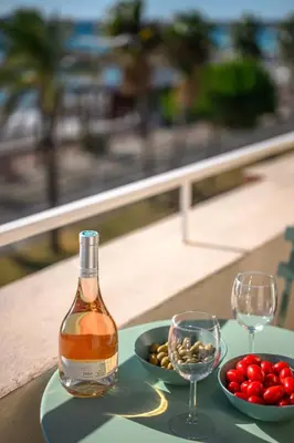 a bottle of wine and two glasses on a table at Vue mer panoramique - Cocon cosy et luxe - Clim et Wifi in Cagnes-sur-Mer
