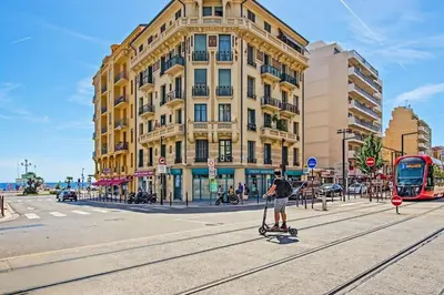 a person riding a scooter on a street in front of a building at Espace Anahit 2 piece meublé avec balcon, proche Tram Magnan et plages BAIL MOBILITE in Nice