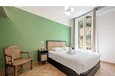 a bedroom with a bed and a chair and a window at Magnifique - 2 chambres - Cœur de Nice avec Balcon in Nice