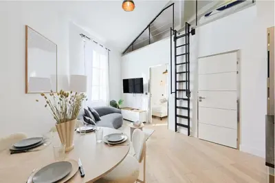 a living room with a table and a room with a ladder at Moderne et lumineux en centre-ville - 2 Chambres in Nice