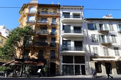 a tall white building with balconies on a street at Nümad Suites in Nice