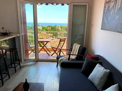 a living room with a blue couch and a balcony at PANORAMIC SEA VIEW with PRIVATE PARKING and AC in Nice