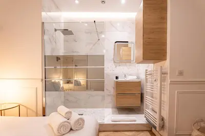 a bathroom with a shower and a bed with towels at La Bellanda - Au coeur du Vieux Nice in Nice