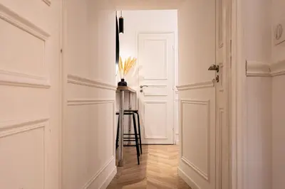a hallway with white walls and a stool in front of a door at La Bellanda - Au coeur du Vieux Nice in Nice