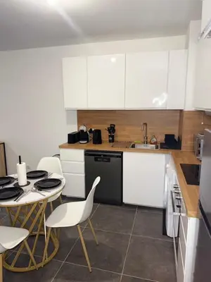 a kitchen with white cabinets and a table and chairs at Le Bonappart T3 Grande Terrasse in Nice