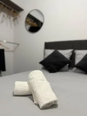 a white towel on a bed with black pillows at Le Bonappart T3 Grande Terrasse in Nice