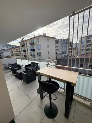 a balcony with a wooden table and chairs on a building at Le Bonappart T3 Grande Terrasse in Nice