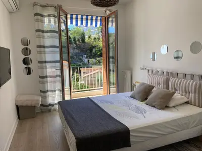 a bedroom with a bed and a large window at 3 pièces 10 min de la mer et du tram in Nice