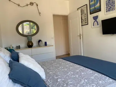 a bedroom with a bed and a mirror and a window at 3 pièces 10 min de la mer et du tram in Nice