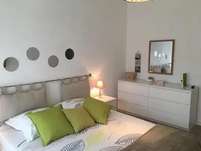 a bedroom with a bed with green pillows and a dresser at 3 pièces 10 min de la mer et du tram in Nice