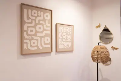 three framed pictures on a white wall with a lamp at L'Adresse du Choeur - Vieux Nice in Nice