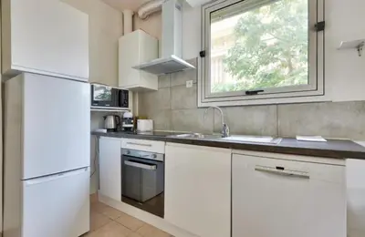 a white kitchen with a sink and a window at Studio Carré Or avec balcon in Nice