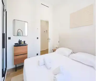 a white bedroom with a white bed and a mirror at Splendide Appartement Neuf au Port de Nice in Nice