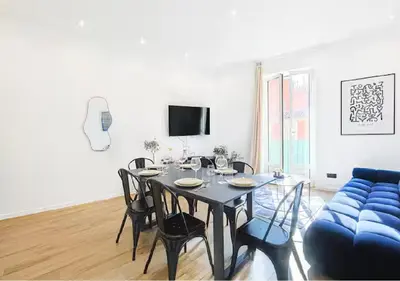 a living room with a table and a blue couch at Splendide Appartement Neuf au Port de Nice in Nice