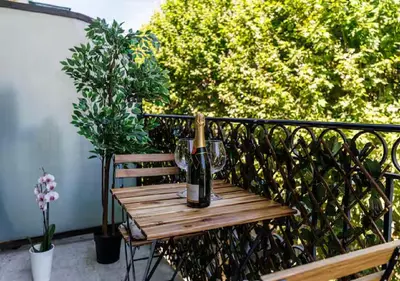 a bottle of wine sitting on a wooden table on a balcony at Le Bijou de Grimaldi Emplacement de Rêve Plage in Nice