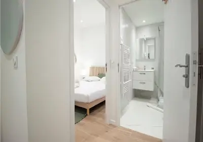 a white bedroom with a bed and a mirror at Nid Douillet au Cœur de Nice avec terrasse et clim in Nice