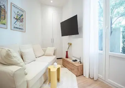 a white living room with a white couch and a window at Nid Douillet au Cœur de Nice avec terrasse et clim in Nice