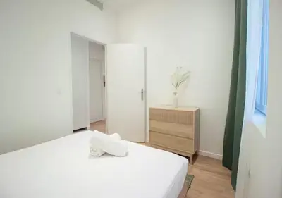 a bedroom with a white bed and a dresser at Nid Douillet au Cœur de Nice avec terrasse et clim in Nice