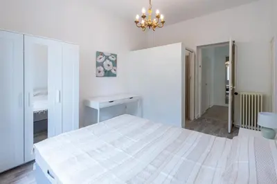a white bedroom with a bed and a chandelier at Happyfew maison Michelet in Nice