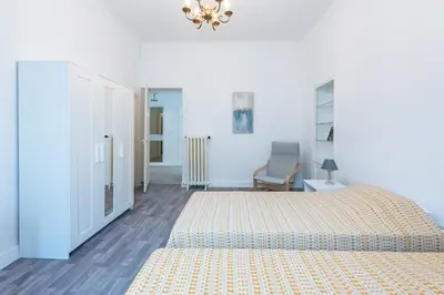 a white bedroom with a bed and a chair at Happyfew maison Michelet in Nice