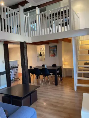 a living room with a table and chairs and a staircase at Duplex Apartment Old Town & Beach in Villefranche-sur-Mer
