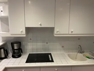 a kitchen with white cabinets and a stove and a sink at Duplex Apartment Old Town & Beach in Villefranche-sur-Mer