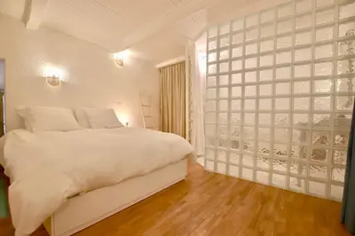 a bedroom with a white bed and a glass wall at Charmant appartement au sein de la vieille ville in Villefranche-sur-Mer