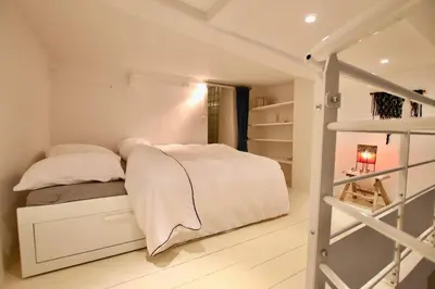 a white bedroom with a bed and a ladder at Charmant appartement au sein de la vieille ville in Villefranche-sur-Mer